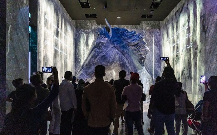 Guide interacting with tourists in front of a large horse sculpture at Expo City Dubai.