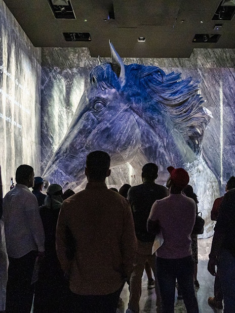 Guide interacting with tourists in front of a large horse sculpture at Expo City Dubai.