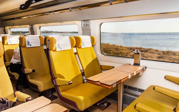 Eurail train interior with yellow seats and table, scenic view through window.