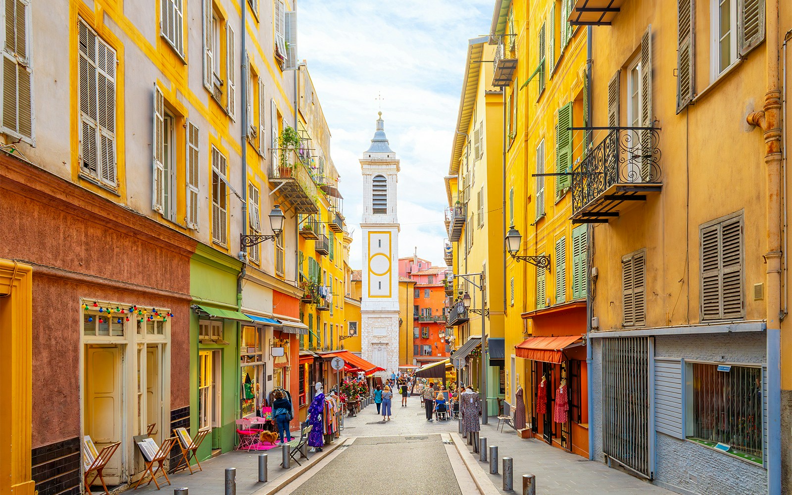 Colorful street in Vieux Nice with shops and a bell tower, Nice