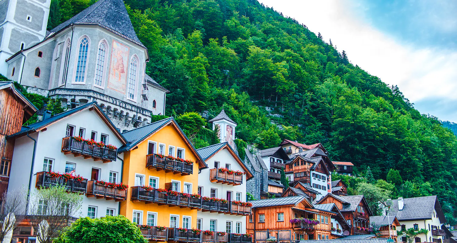 Colorful houses and church in Hallstatt, Austria, surrounded by lush greenery, part of Vienna day trip.