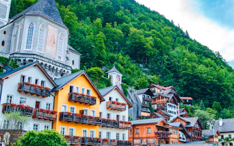 Colorful houses and church in Hallstatt, Austria, surrounded by lush greenery, part of Vienna day trip.