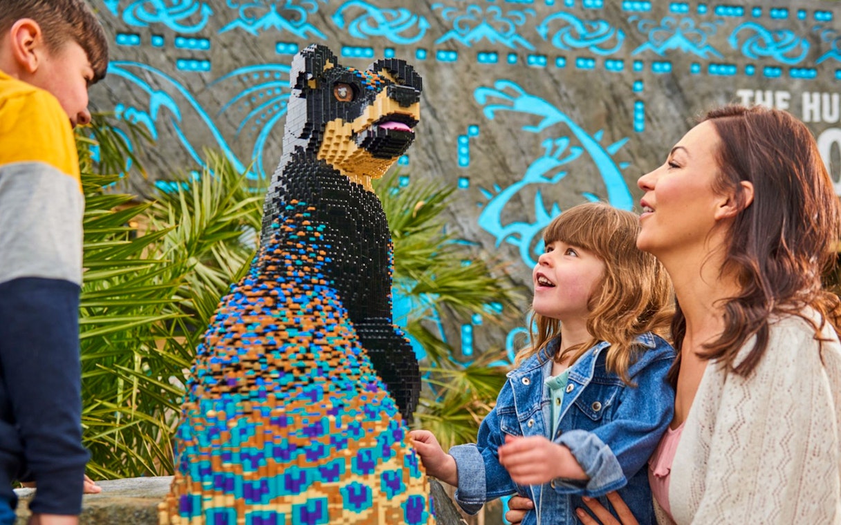 Child and adult admiring LEGO sculpture at LEGOLAND Windsor Resort.