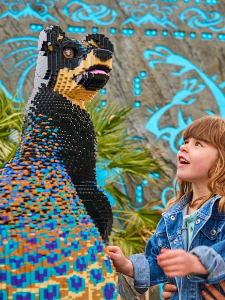 Child and adult admiring LEGO sculpture at LEGOLAND Windsor Resort.