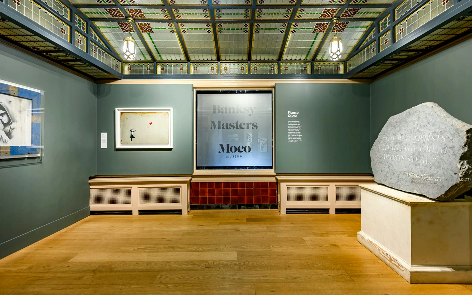 Moco Museum Amsterdam Banksy exhibit with framed artwork and Picasso quote on stone.