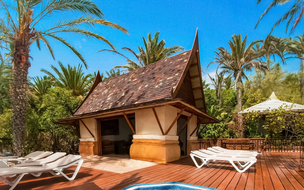 Cabana with loungers at Siam Park surrounded by palm trees.