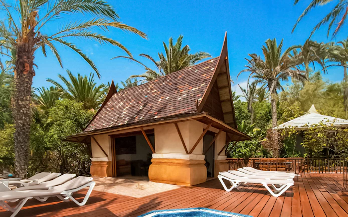 Cabana with loungers at Siam Park surrounded by palm trees.