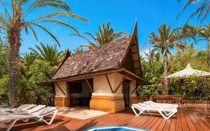 Cabana with loungers at Siam Park surrounded by palm trees.