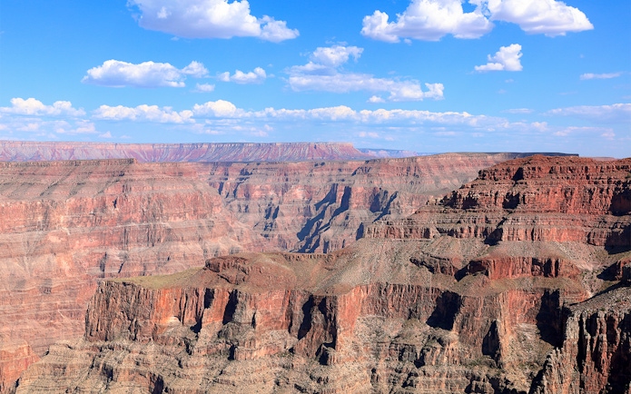 Grand Canyon West Rim with layered rock formations under a blue sky.