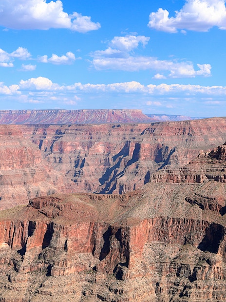 Grand Canyon West Rim with layered rock formations under a blue sky.