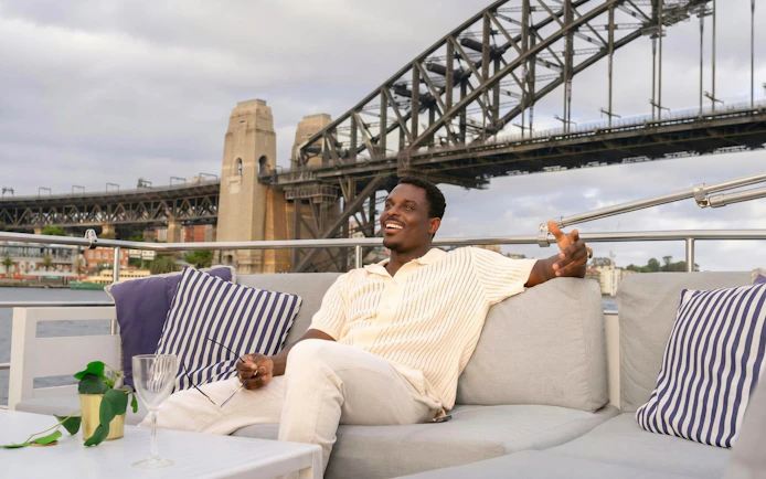 Man relaxing on a Sydney Harbour cruise with Harbour Bridge in the background.