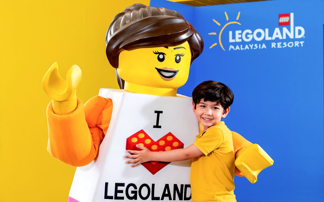 Child embracing LEGO character at Legoland Malaysia Resort.
