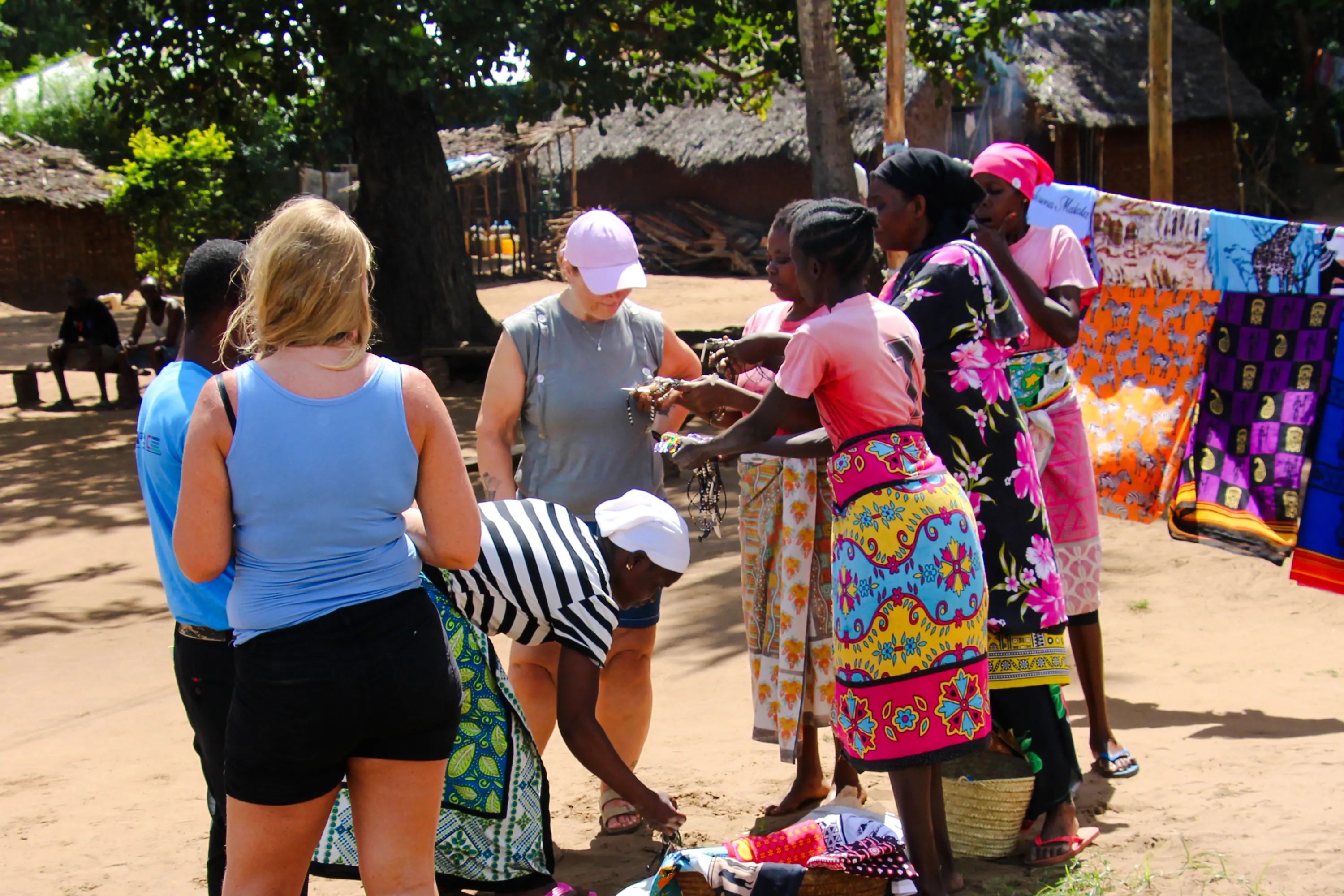 Tourists interacting with local vendors at a village market during the Giriama cultural dance show in Diani Beach.