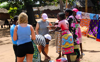 Tourists interacting with local vendors at a village market during the Giriama cultural dance show in Diani Beach.