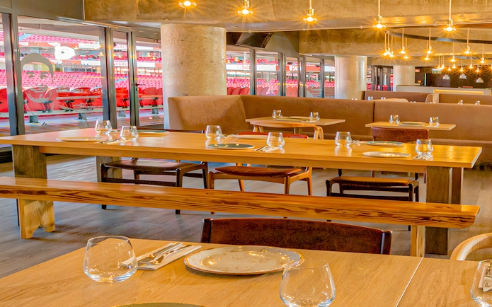 Restaurant interior with tables set, overlooking Benfica Stadium seating area.