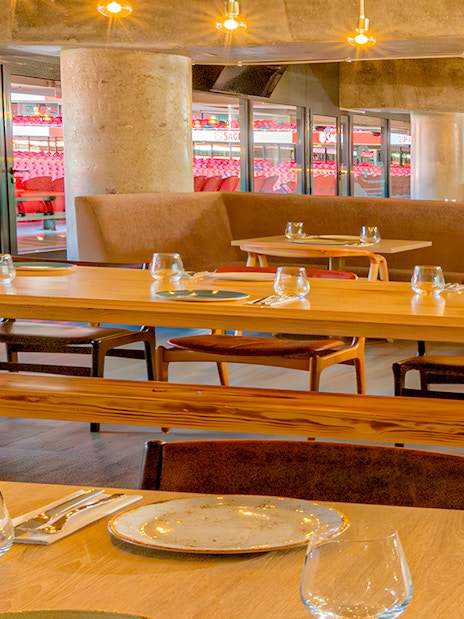 Restaurant interior with tables set, overlooking Benfica Stadium seating area.
