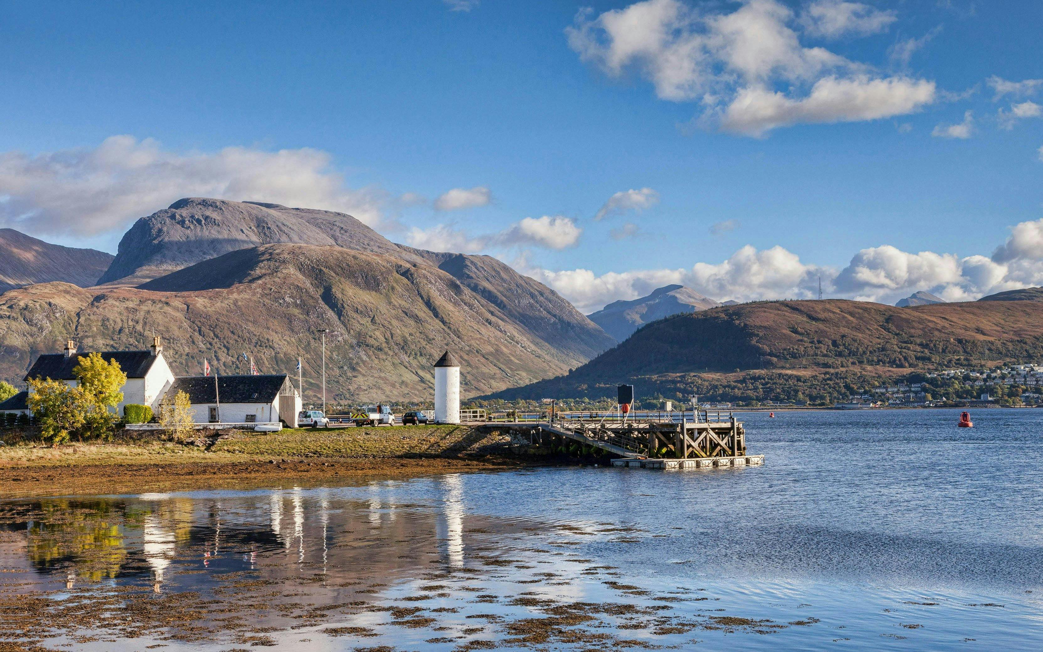 Fort William landscape with Ben Nevis and loch, featuring a small pier and white buildings.