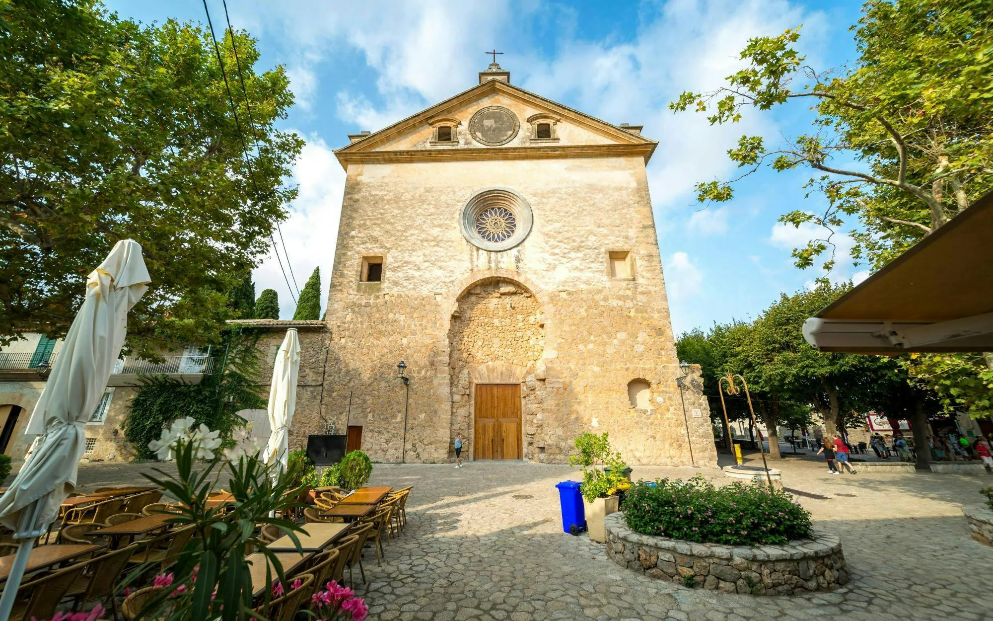 Parish Church of Sant Bartomeu facade in Valldemossa, Mallorca, Spain with outdoor seating.