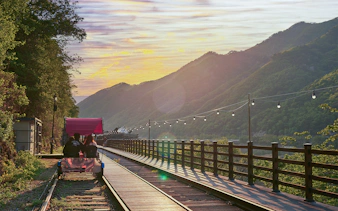 Couple riding Gangchon Railbike at sunset with mountain view in Korea.