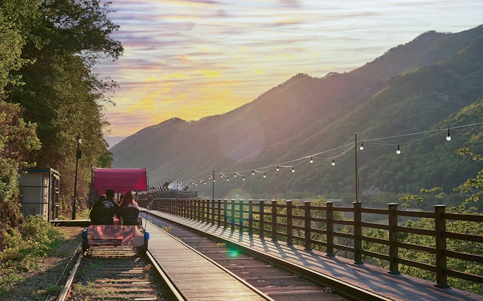 Couple riding Gangchon Railbike at sunset with mountain view in Korea.