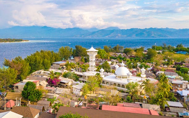 Aerial view of Gili Islands village with mosque and ocean backdrop, Northern Coast snorkeling trip.