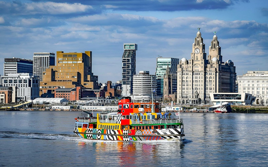 Colorful ferry on River Mersey with Liverpool skyline in the background.