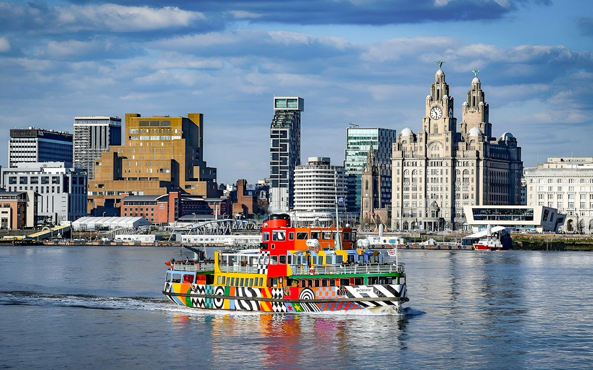 Colorful ferry on River Mersey with Liverpool skyline in the background.