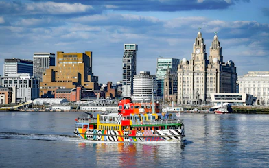 Colorful ferry on River Mersey with Liverpool skyline in the background.