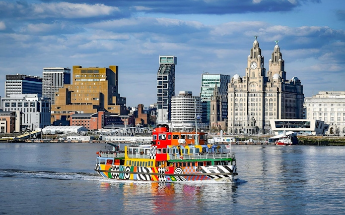 Colorful ferry on River Mersey with Liverpool skyline in the background.