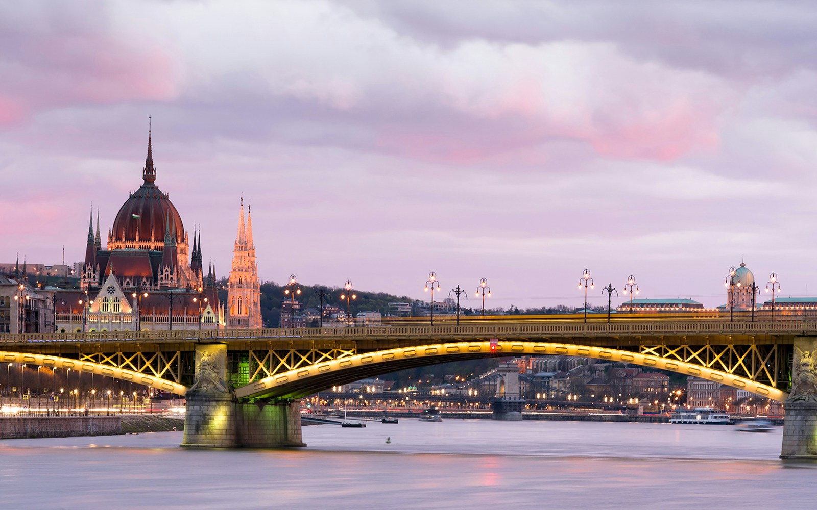 Danube River evening cruise in Budapest with dinner and champagne, illuminated cityscape in background.