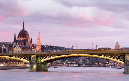 Parliament building and bridge over Danube River at sunset in Budapest.