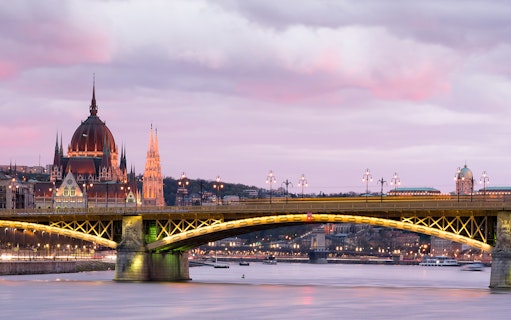 Parliament building and bridge over Danube River at sunset in Budapest.