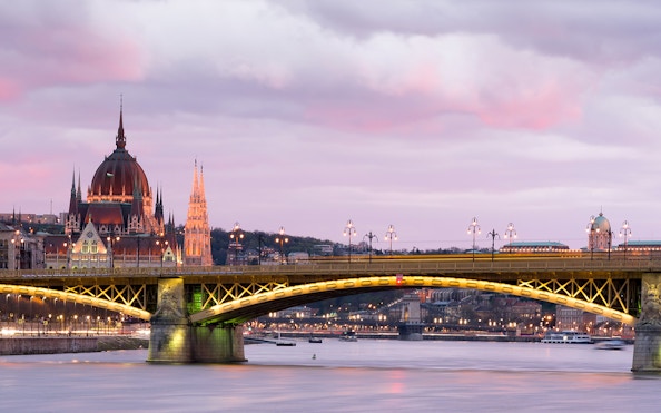 Parliament building and bridge over Danube River at sunset in Budapest.