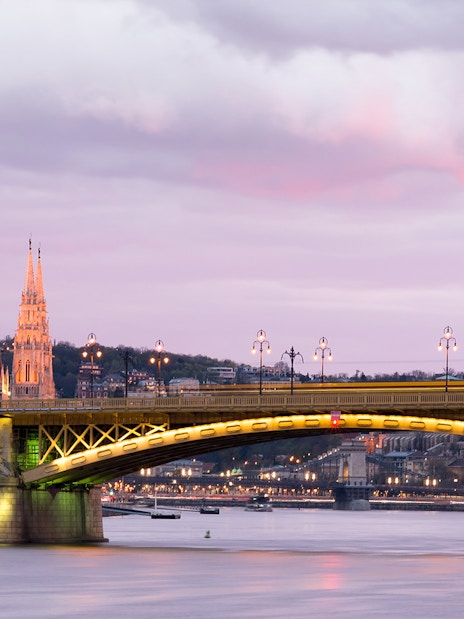 Parliament building and bridge over Danube River at sunset in Budapest.