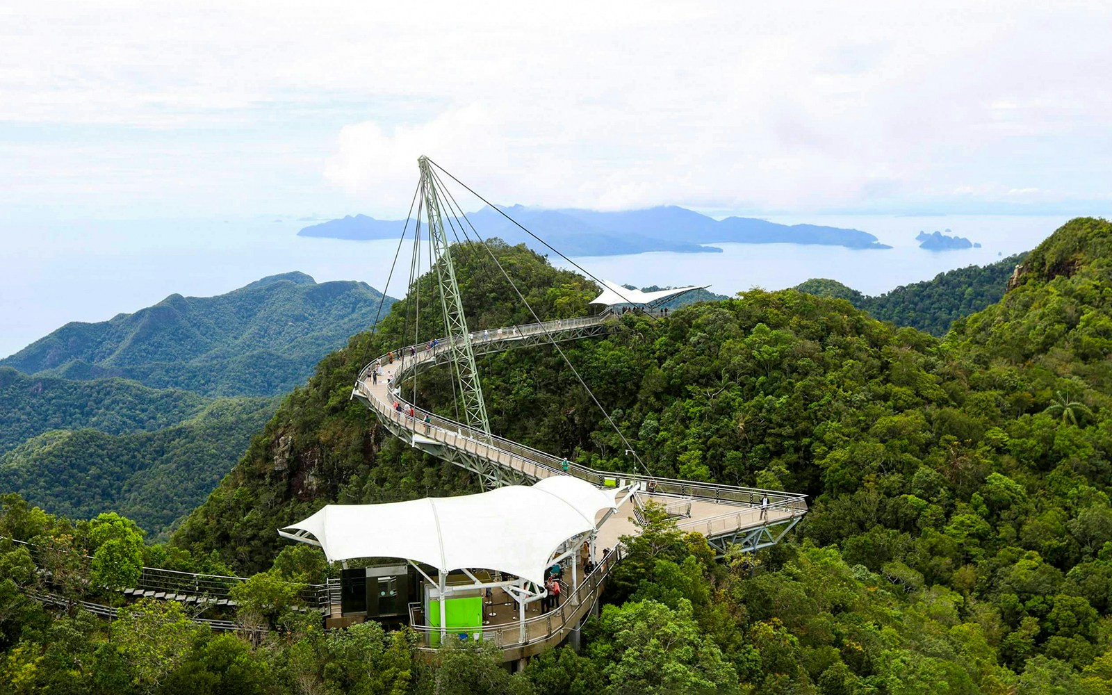 Langkawi Sky Bridge with tourists walking and panoramic mountain views.