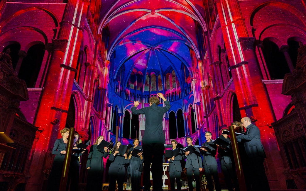 Choir performing under colorful lights at Manchester Cathedral during LUMINISCENCE 360° Immersive Show.