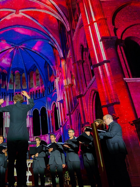 Choir performing under colorful lights at Manchester Cathedral during LUMINISCENCE 360° Immersive Show.