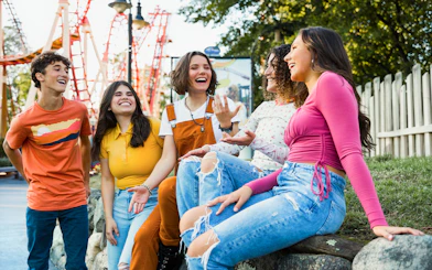 Group of friends enjoying a day at Six Flags New England with roller coasters in the background.