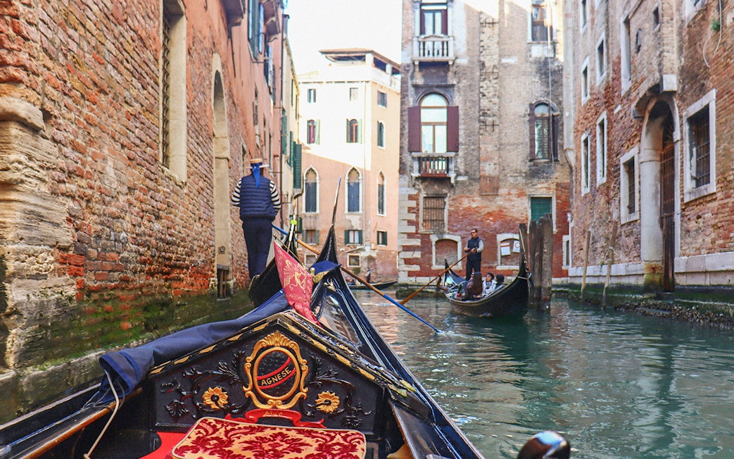Gondola ride through narrow canal in Venice with tourists and gondolier.