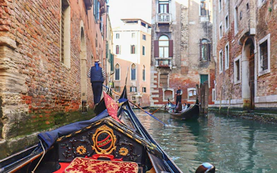 Gondola ride through narrow canal in Venice with tourists and gondolier.