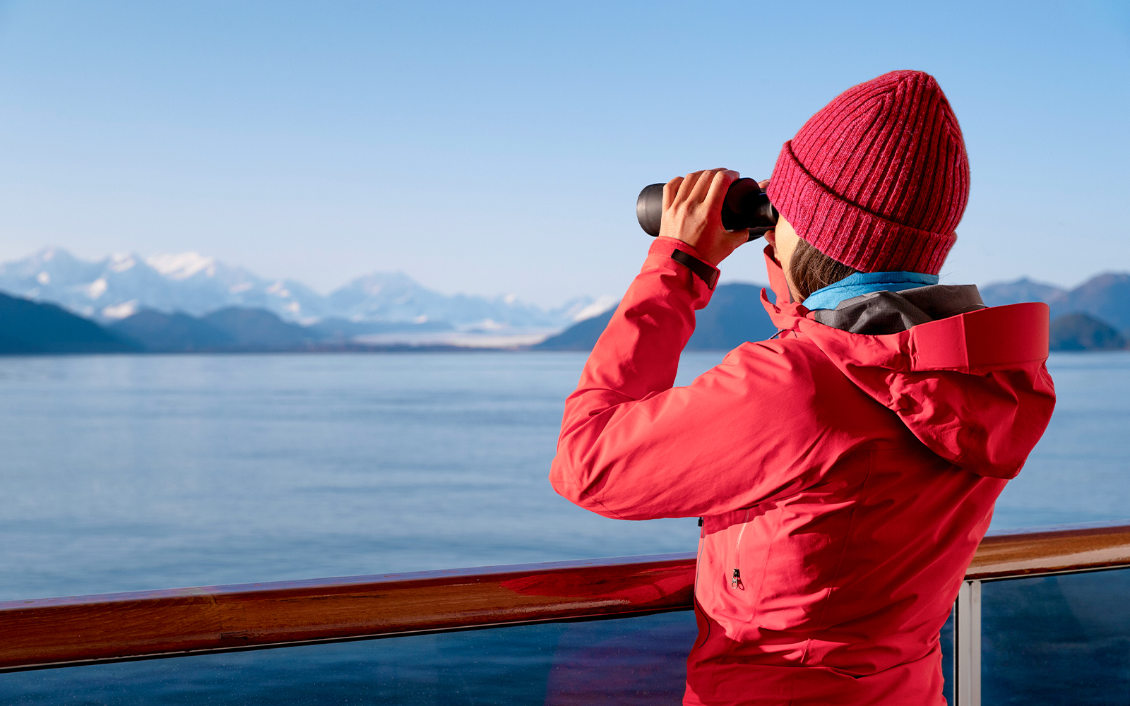 Passenger using binoculars to view distant mountains on a scenic tour.