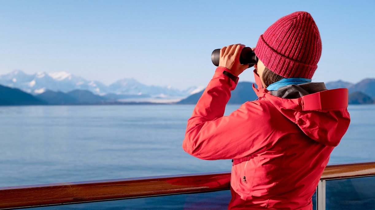 Passenger using binoculars to view distant mountains on a scenic tour.