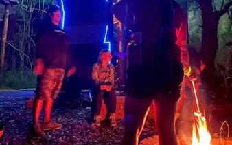 Campfire gathering during night zipline adventure with people roasting marshmallows.