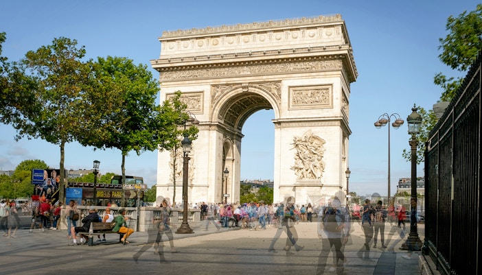 People exploring Arc de Triomphe, Paris, with detailed architectural features visible.