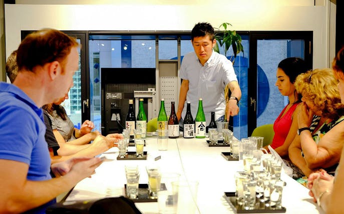 Sake tasting session at Kyoto Insider Sake Experience with bottles displayed on the table.