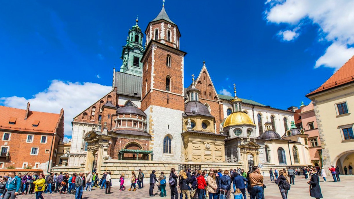Wawel Castle courtyard with tourists in Krakow, featuring cathedral domes and historic architecture.