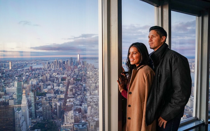 Couple enjoying New York City skyline view from Empire State Building Observatory.