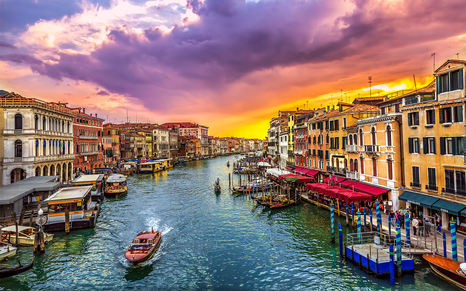Gondola on Venice canal at sunset with colorful buildings.
