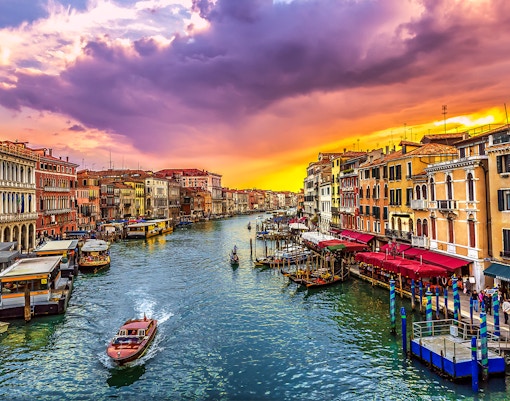 Gondola on Venice canal at sunset with colorful buildings.