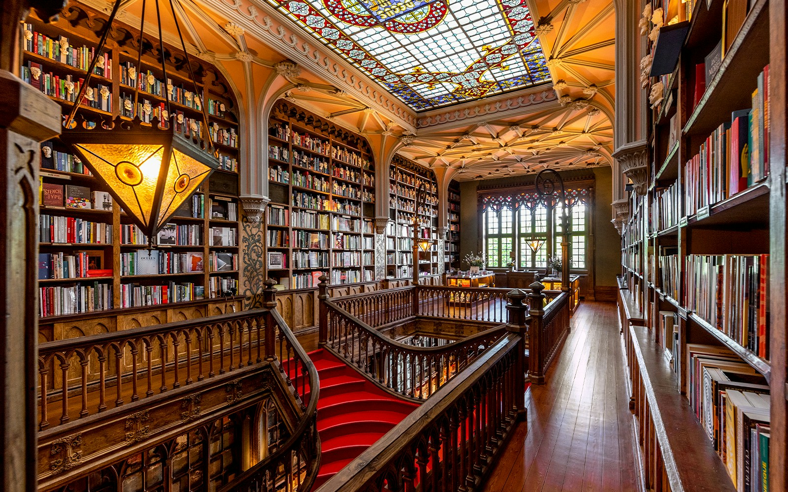 Lello Library 1st floor with ornate wooden bookshelves and stained glass ceiling in Porto, Portugal.